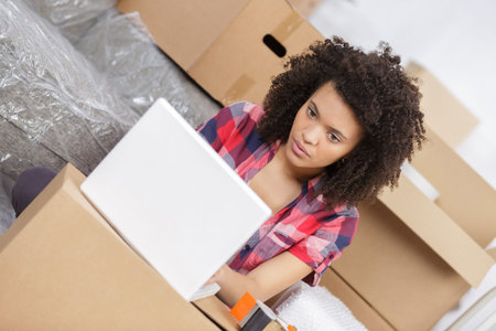woman sitting on the floor near a boxes with laptop