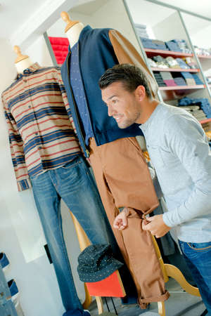 Man in shop holding trouser leg on mannequinの写真素材