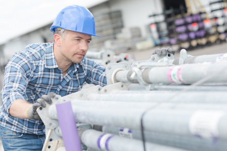 Worker pushing stack of scaffold poles