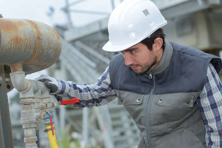 Man inspecting pipeworkの写真素材