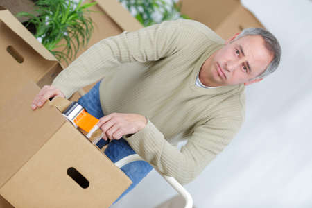 Depressed man packing cardboard boxesの写真素材
