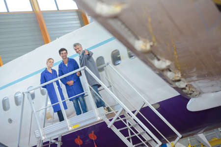 Three people on platform next to aircraftの写真素材