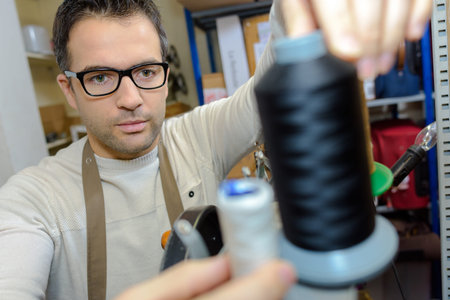 Spectacled man adjusting reel of cotton