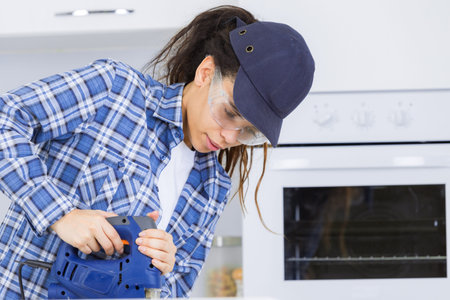 Woman using jigsaw in kitchen