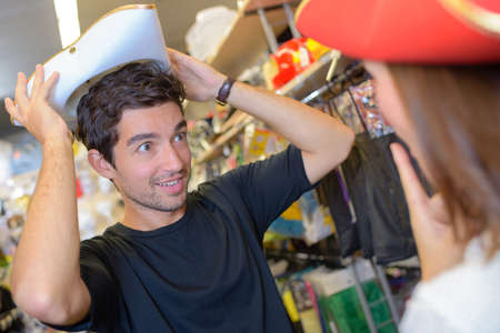 Couple trying on hats in fancy dress shopの写真素材