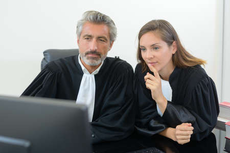 Male and female magistrates looking at computerの写真素材