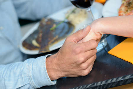 Closeup of couple holding hand over mealの写真素材