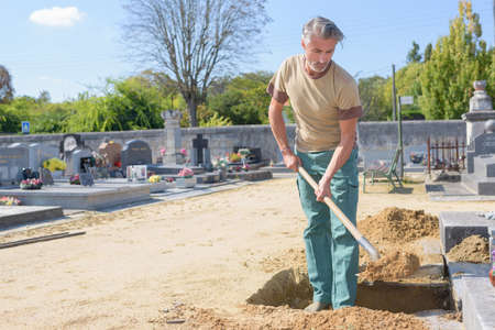 Man shovelling sand into graveの写真素材