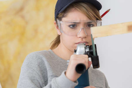 woman carpenter cutting the wooden frameの写真素材