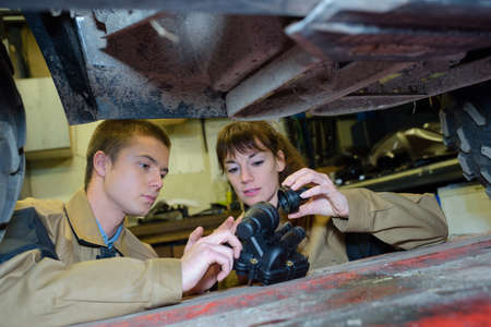 Mechanics holding replacement part under vehicleの写真素材