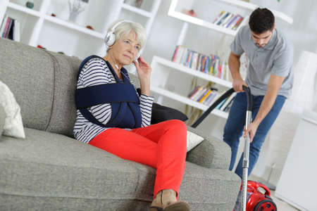 young man home help cleaning ladys living roomの写真素材