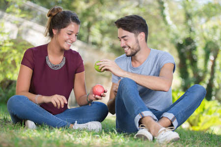 young couple in the park sitting on the grassの写真素材