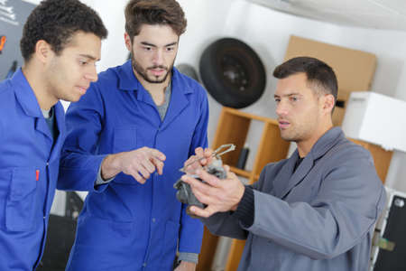 teacher helping students training to be car mechanicsの写真素材