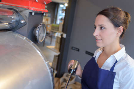 young female worker near tank on beer brewery factoryの写真素材