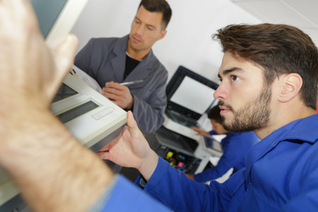 young technician fixing broken photocopier machine