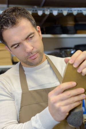 joyful shoe repairman replacing heeltaps on shoe at workshopの写真素材