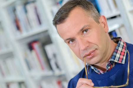 Portrait of man with arm of spectacles in his mouthの写真素材