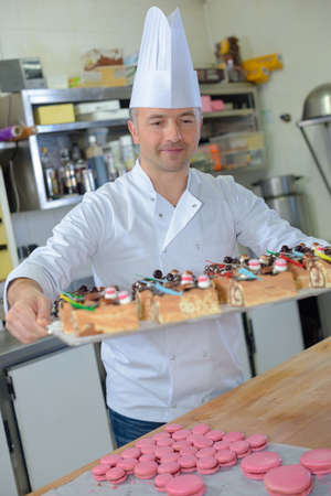 pastry chef holding delicious looking cakes and pastriesの写真素材