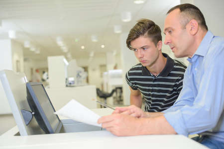 Two men looking at paperwork and equipmentの写真素材