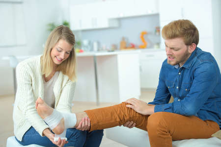 helping boyfriend with damaged ankleの写真素材