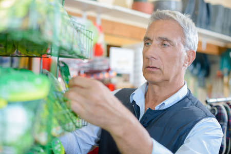 Man choosing from rack of seedsの写真素材
