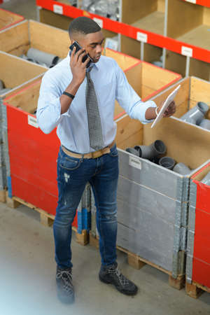 Worker in plumbing supplies shop, using telephoneの写真素材