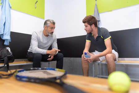 tennis coach talking to player in changing roomの写真素材