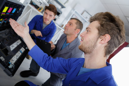 Three men looking at ink cartridges in photocopier