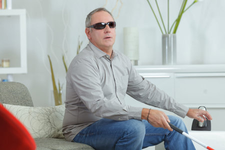 Blindman at home wearing glasses and holding stickの写真素材