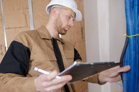 plumber with clipboard standing in front pipes