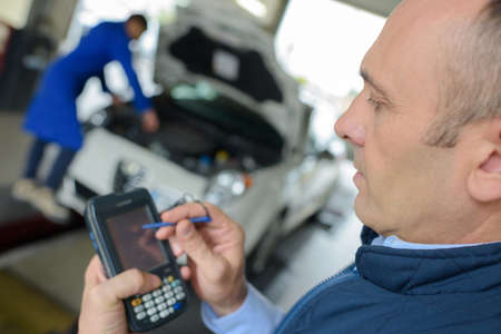 Garage mechanic using electronic device with stylusの写真素材