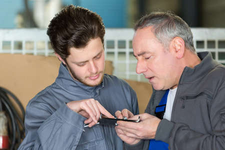 workmen inserting screw into metal plateの写真素材