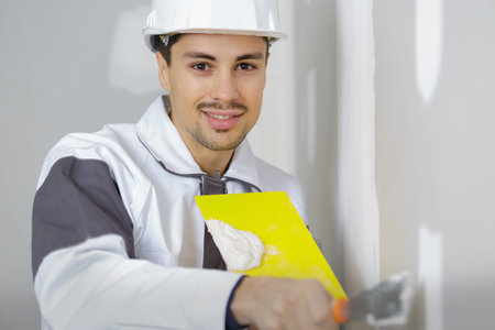 plasterer at indoor wall renovation decoration with palette knife