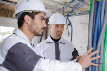 line electrician builder engineer workers at indoor construction siteの写真素材