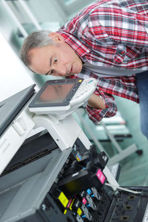 Man bending down to photocopierの写真素材
