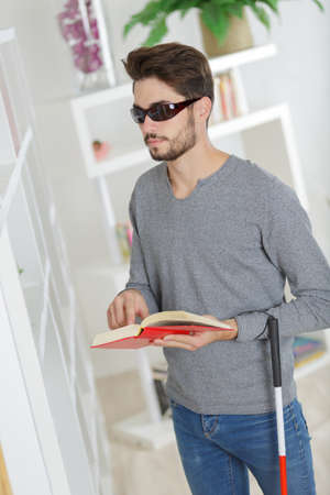 Man with sight impairment reading braille bookの写真素材