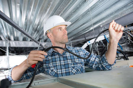 Electrician installing cables in roofの写真素材