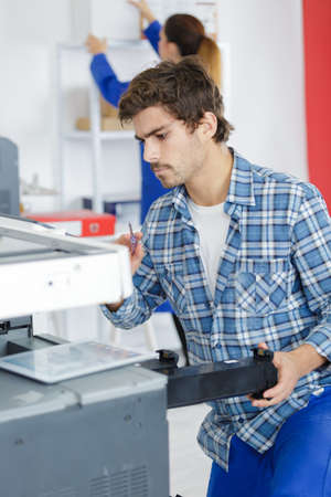 Man repairing office photocopierの写真素材