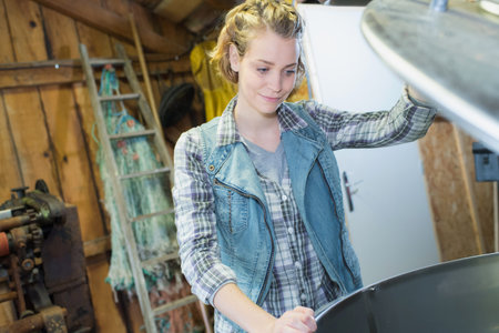 Woman looking into large metal container