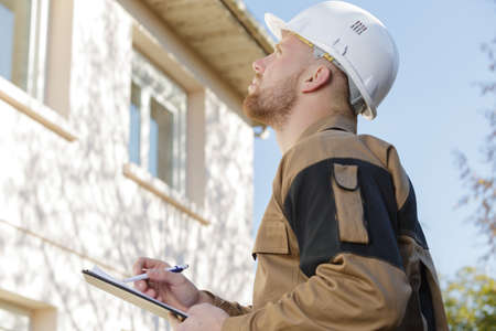 builder in hardhat with clipboard outdoorsの写真素材