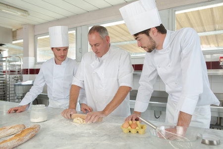 young men professional pastry cook at work in kitchen