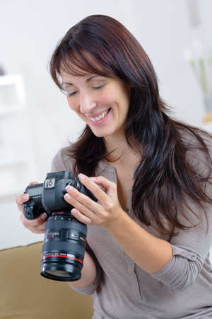 happy woman photographer takes images with dslr cameraの写真素材