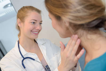 female doctor checking womans throatの写真素材