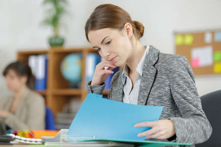 attractive female office worker checks something in her folderの写真素材