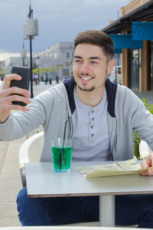 handsome man taking selfie with smartphone in cafe