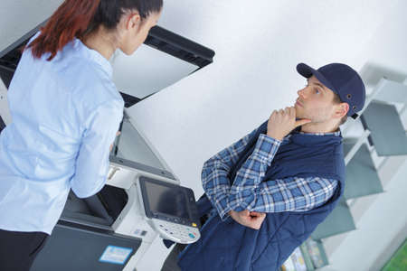 frustrated business woman opening photocopy machine in officeの写真素材