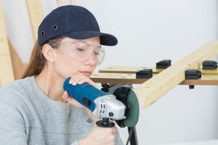 Woman using grinder on edge of wood