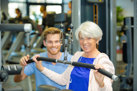 sport coach training senior woman with stretching exercisesの写真素材