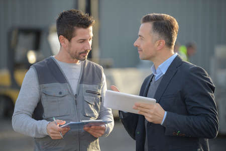 workers discussing over tablet computer in shipping yardの写真素材