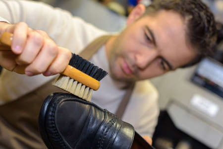 worker polishing using a horsehair brush for leather shoeの写真素材